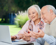 Una coppia anziana chiacchiera davanti a un laptop