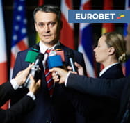 Un politico parla a dei giornalisti e il logo di Eurobet